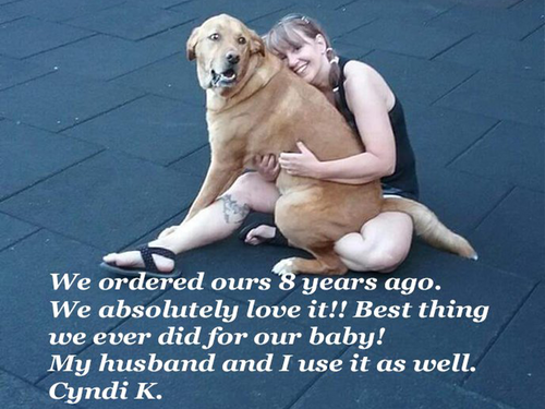 Woman sitting on a mat hugging her dog, smiling at the camera